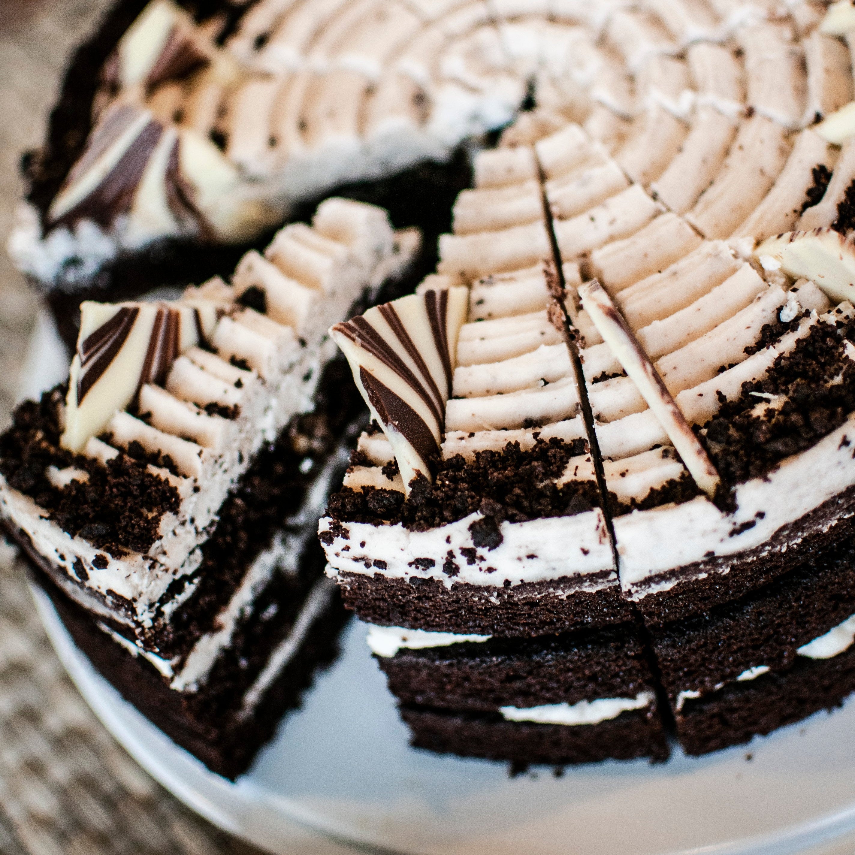 Chocolate cake with white frosting and a slice taken out on a white plate.